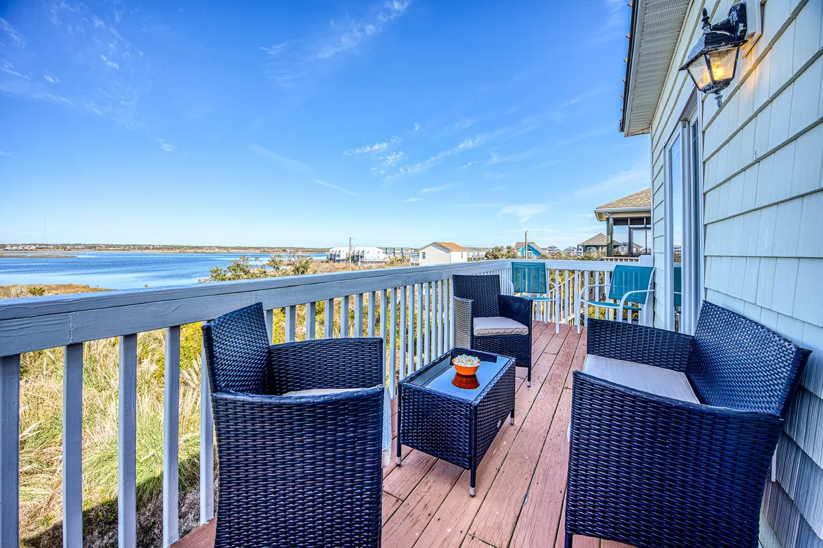 An outdoor seating area with a table and decorative plant overlooking the water. The scene is set for morning coffee or sunset cocktails while enjoying panoramic Intracoastal views, tying the indoor spaces to the home's spectacular porch and sun deck.