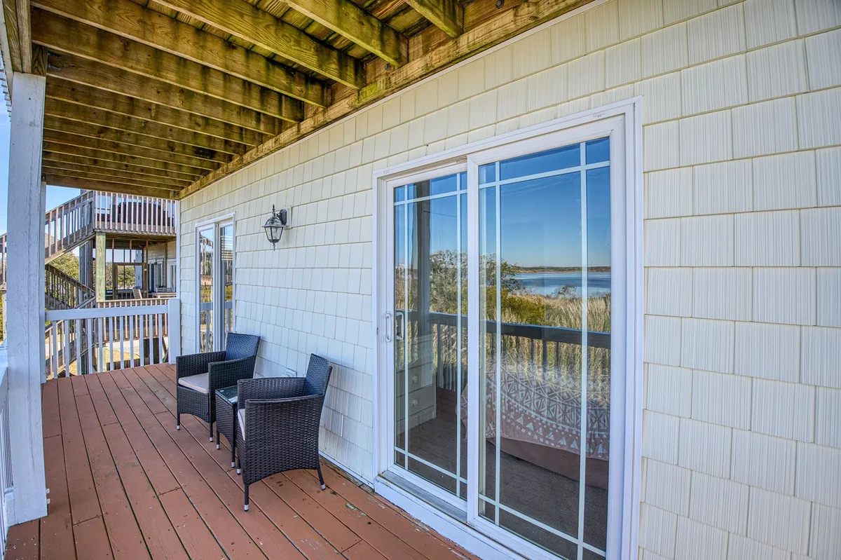 This image shows a tranquil balcony with comfortable chairs facing a scenic view, accessed through sliding glass doors. The setting suggests a quiet spot perfect for sipping morning coffee or enjoying the sunset after a day of local exploration.