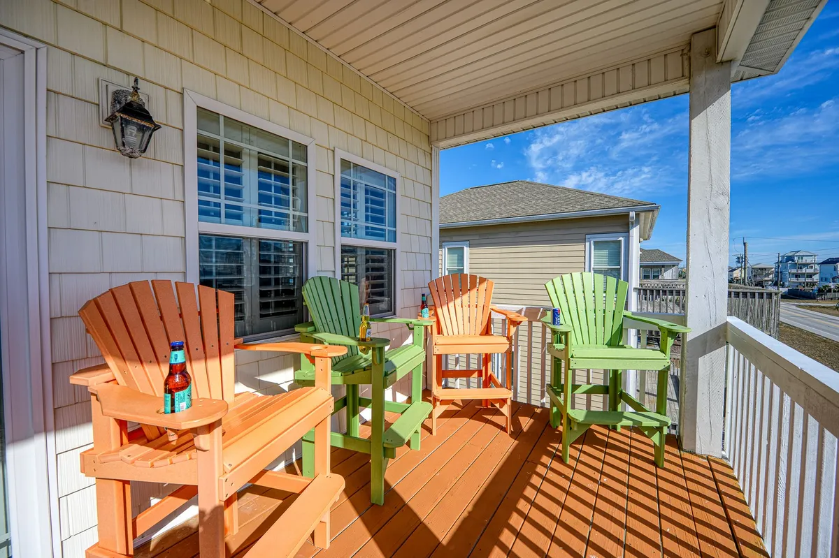 A cheerful exterior image showcasing colorful chairs on a deck, complemented by large windows and a sturdy railing. The atmosphere is lively and social, perfect for relaxing in the ocean breeze or enjoying a sunset.