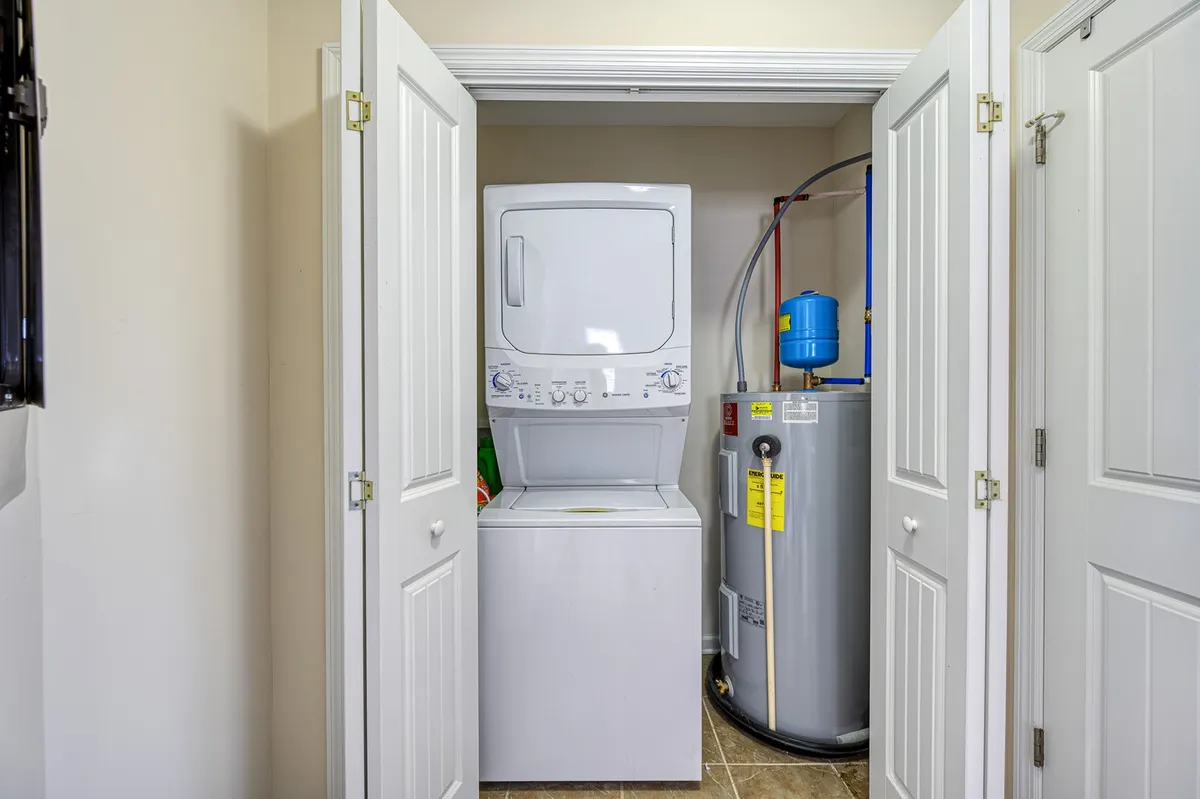 A practical interior view of a laundry area featuring a washer, dryer, and water heater, designed for efficiency and convenience. The space is clean, organized, and bright, emphasizing utility and self-sufficiency.