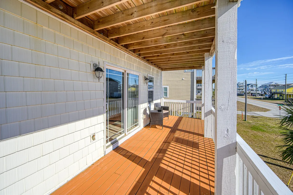 An inviting exterior shot of the home's wooden decking, featuring sliding glass doors that lead to a comfortable outdoor seating area. The setting captures both sunrise and starlit evening moods, suggesting a tranquil space for relaxation and socializing.