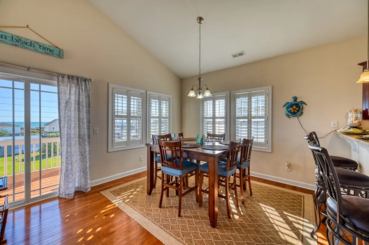 A cozy dining area featuring a table with bar stools and a window that lets in ample sunlight. The setup encourages both family meals and casual breakfasts, complementing the adjacent kitchen space. The mood is intimate and perfect for sharing stories and meals together.